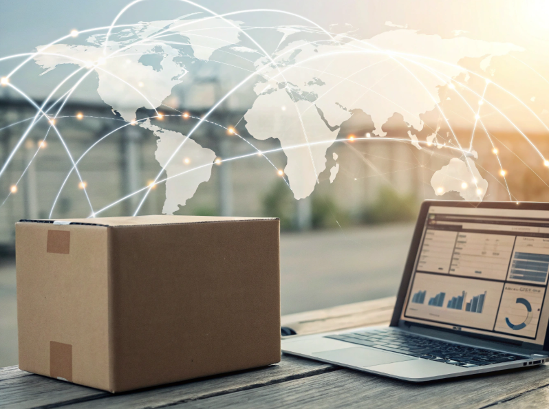 Paczka kurierska obok otwartego laptopa z danymi analitycznymi na tle mapy świata z siecią połączeń